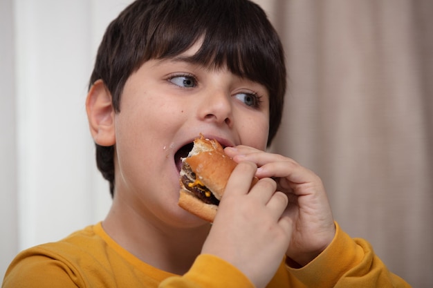 Leuke gezonde preschool jongen jongen eet hamburger zittend op school