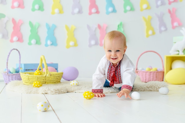 Foto leuke glimlachende baby in traditioneel borduurwerk in gekleurde pasen-decoratie