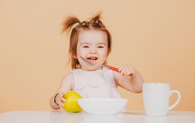 Leuke grappige baby's die babyvoeding eten grappig lachend meisje met lepel eet zichzelf op