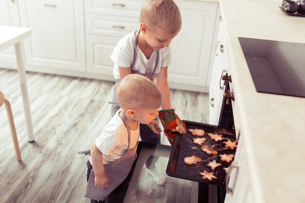 Leuke grappige blonde jongens die peperkoekkoekjes koken en bereiden