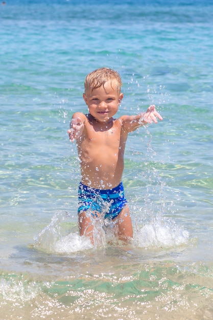 Leuke grappige gelukkige kleine jongen spelen in de golven van het water op zee oceaan op een zonnige dag