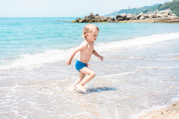 Leuke grappige kleine jongen spelen en plezier hebben aan zee zomer strandvakantie jeugd levensstijl...