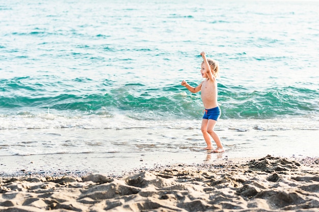 Leuke grappige kleine jongen spelen en plezier hebben aan zee zomer strandvakantie jeugd levensstijl...