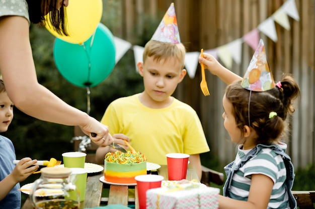 Leuke grappige negenjarige jongen die zijn verjaardag viert met familie of vrienden en zelfgebakken cake eet in een achtertuin Verjaardagsfeestje voor kinderen