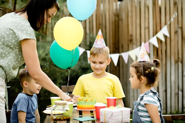 Leuke grappige negenjarige jongen die zijn verjaardag viert met familie of vrienden en zelfgebakken cake eet in een achtertuin Verjaardagsfeestje voor kinderen