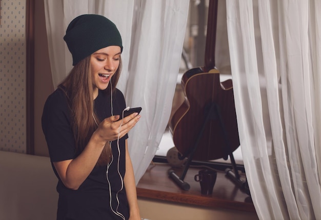 Leuke hipstervrouw die muziek luistert dichtbij gitaar