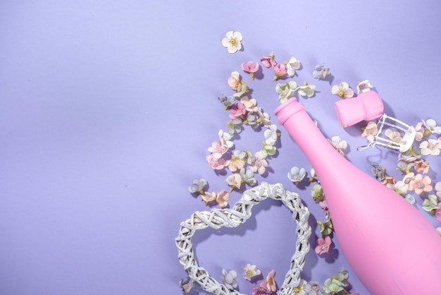 Leuke hooggekleurde Valentijnsdag achtergrond, met roze gekleurde champagnefles, lentebloesem bloemen, klein hart decor, op violet zeer peri kleur achtergrond flatlay kopie ruimte