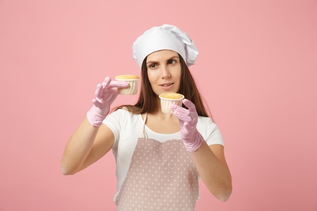 Leuke huisvrouw chef-kok kok banketbakker bakker in wit t-shirt, toque chef-koks hoed koken houden zoet geïsoleerd op roze pastel achtergrond in studio. Proces voor het maken van cupcakes. Bespotten kopie ruimte voedsel concept.