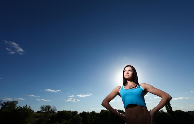 Leuke jonge atletische vrouw die zich tegen de blauwe hemel bevindt