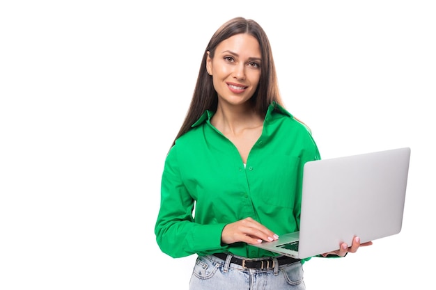 Leuke jonge bruine, bruinharige, carrièreachtige vrouw met make-up in een groene blouse werkt op afstand op het gebied van IT.