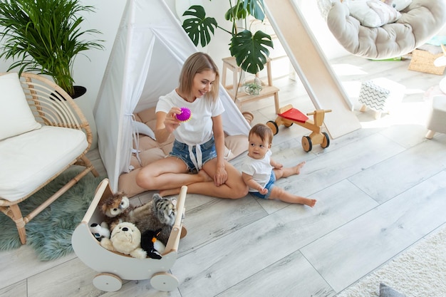 Leuke jonge moeder met haar kleine dochter spelen in de speelkamer met speelgoed Moederschap