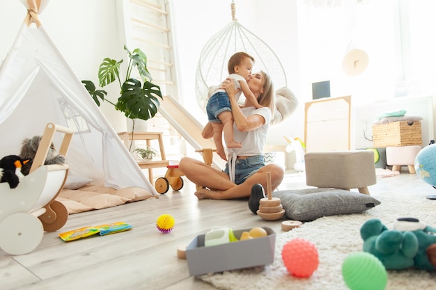 Leuke jonge moeder met haar kleine dochter spelen in de speelkamer moederlijke zorg en liefde