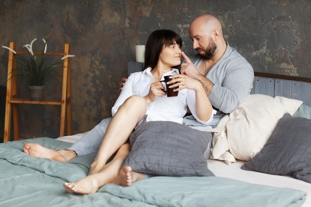 Leuke jonge paar het drinken ochtendkoffie die in bed ligt