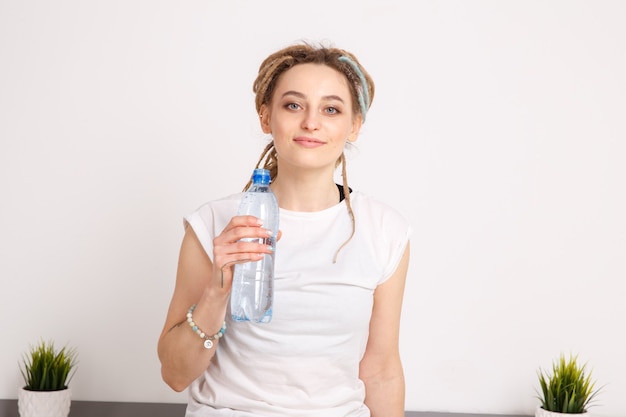 Leuke jonge vrouw drinkwater tijdens yoga-oefeningen.