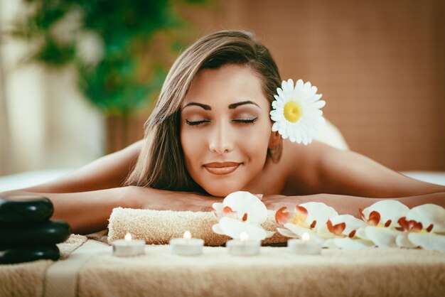 Leuke jonge vrouw geniet tijdens een huidverzorgingsbehandeling in een spa.