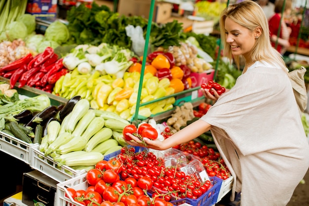 Leuke jonge vrouw het kopen van groenten op de markt