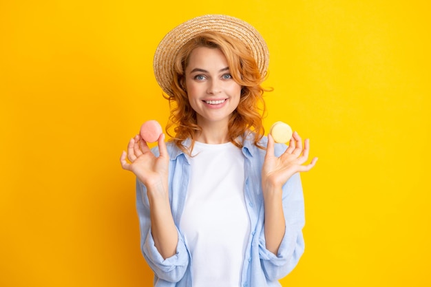 Leuke jonge vrouw houden bitterkoekjes Dieet dieet concept Mooi glimlachend jong meisje kleurrijke bitterkoekjes eten op gele achtergrond