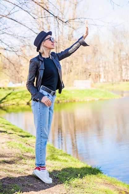 Leuke jonge vrouw in denim zwarte jas en hoed buitenshuis mode portret