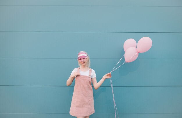 Leuke jonge vrouw in roze kleren die zich met ballons bevinden