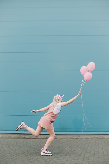 Leuke jonge vrouw in roze kleren die zich met ballons bevinden