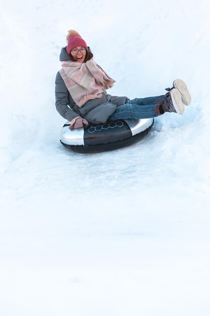 Leuke jonge vrouw met snowtubing winteractiviteit, glijbaan van sneeuwheuvel