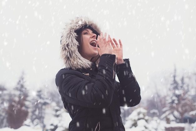 Leuke jonge vrouw onder showflakes in de winter