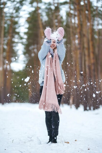 Leuke jonge vrouw speelt met sneeuw in het bos Winterlevensstijl geluk emoties natuur Kerst