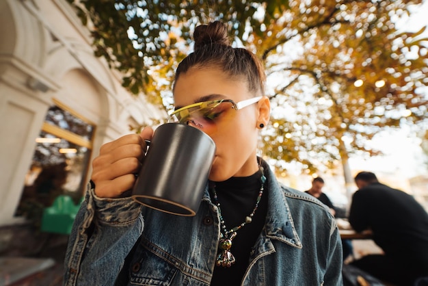 Leuke jonge vrouw terwijl ze thee drinkt in een modern straatcafé