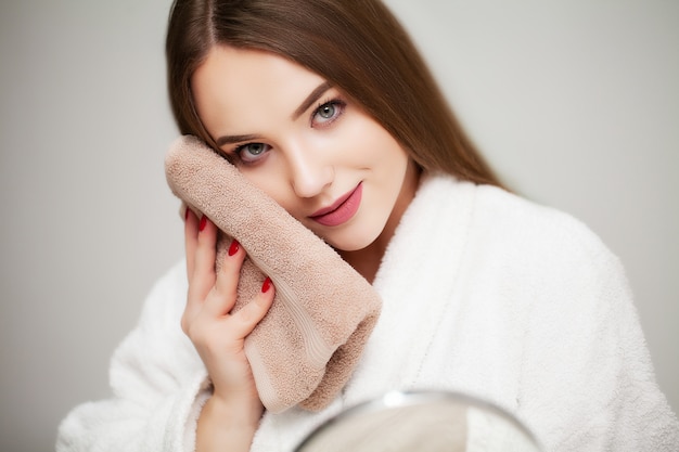 Leuke jonge vrouw veegt het gezicht handdoek na het douchen af