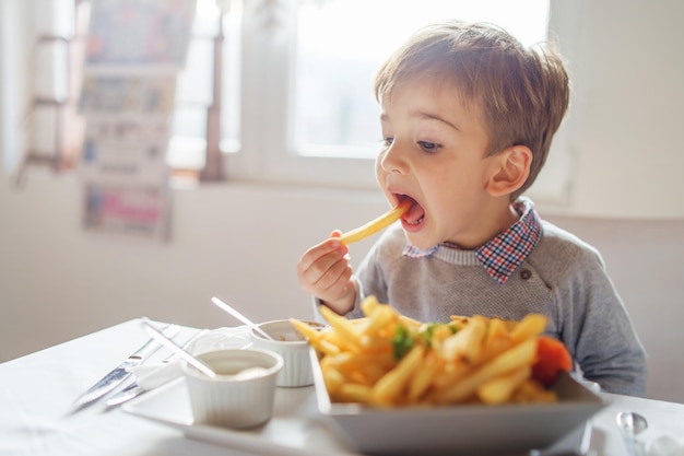 Leuke jongen die aan tafel eet.