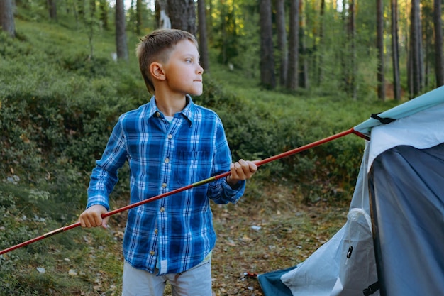 leuke jongen die een tent opzet Familiekampeerconcept