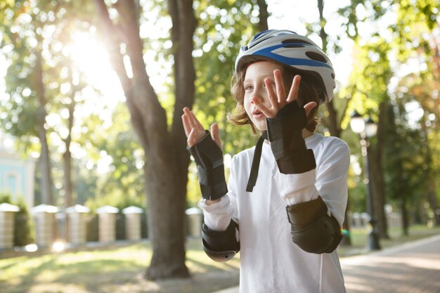 Leuke jongen die geniet van schaatsen in het park, beschermende skateuitrusting draagt