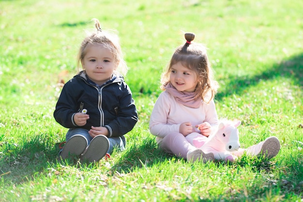 Leuke jongen en meisje zitten op gras op zomerveld baby kind in groen gras op lentegazon kleine kinderen