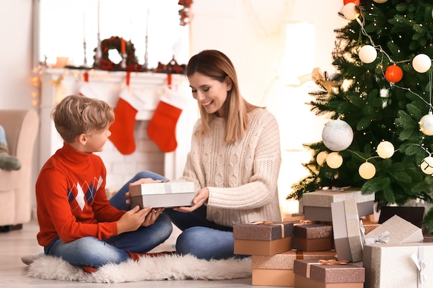 Leuke jongen en zijn moeder met kerstcadeaus thuis