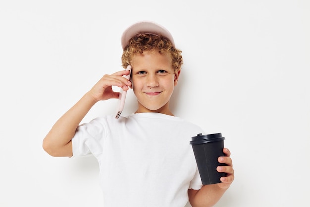 Leuke jongen in een witte t-shirtpet met een telefoon in een glas met een drankje geïsoleerde achtergrond ongewijzigd