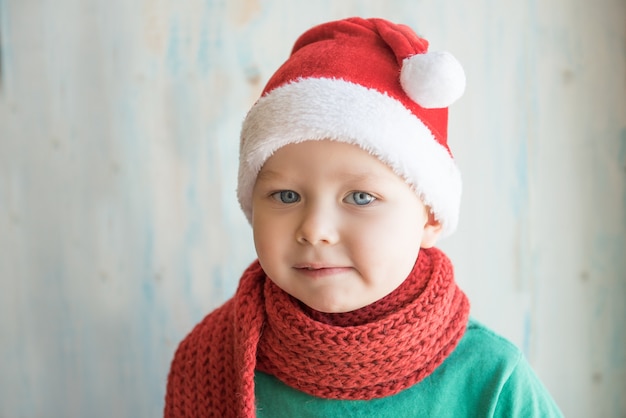 Leuke jongen in kerstmuts en rode sjaal