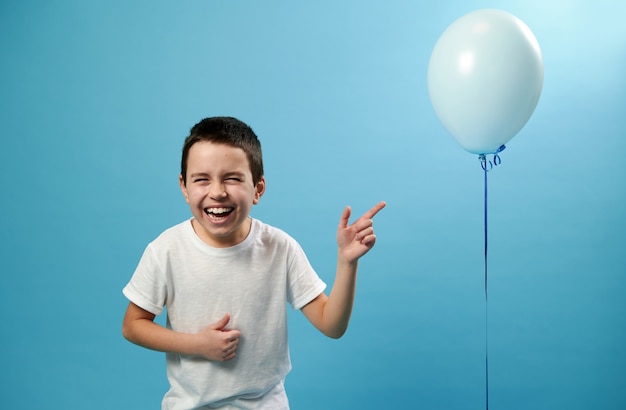 Leuke jongen lachen en vinger omhoog op een ballon