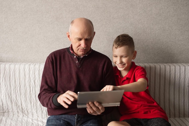 Leuke jongen leert opa om berichten op een tablet te schrijven