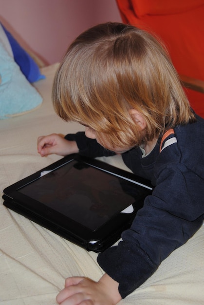 Foto leuke jongen met blond haar die thuis een digitale tablet gebruikt.