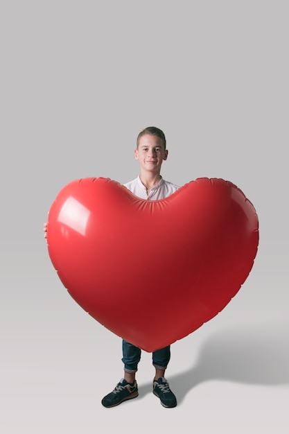 Leuke jongen met hartvormige ballon op lichte achtergrond