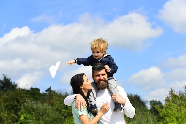 Leuke jongen met ouders die buiten spelen Geniet van de kindertijd Vader geeft zoon een ritje op de rug en knuffel vrouw in het park Generatie grappige tijd Zorgeloze vader en zoon genieten van buiten