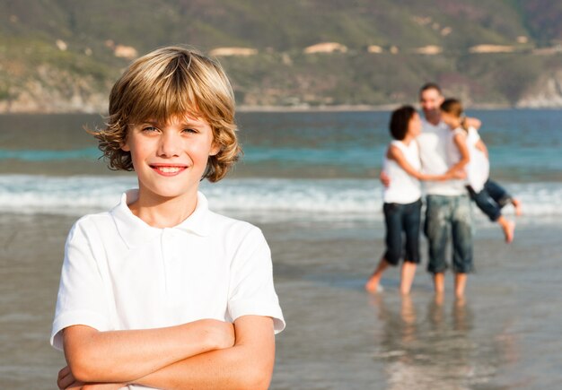 Leuke jongen op een strand met zijn ouders en zijn zuster op achtergrond