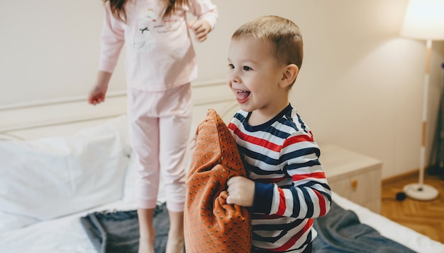 Leuke jongen speelt met een kussen op de bank met zijn zus