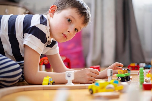 Leuke jongen speelt met speelgoed spoorweg weg thuis of in de kleuterschool op de vloer