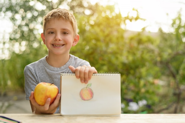 Leuke jongen toont getekende appel. Creatief concept.