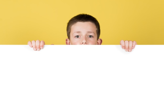 Leuke jongen verstopt achter een wit reclamebord