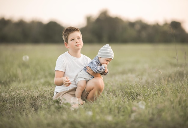 Leuke jongens buiten oudere broer knuffels jongere en zorgen voor broer of zus Concept broers en zussen en openhartige levensstijl