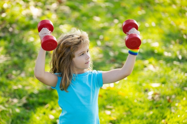 Leuke jongenstraining in park kid sport kind oefenen met halters sportief kind met dumbbell outdoo