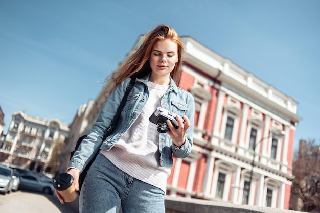 Leuke kaukasische vrouwentoerist die met een retro camera in de stad lopen