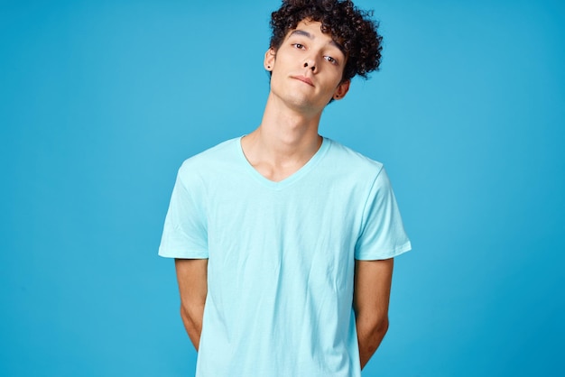 Leuke kerel met krullend haar blauw T-shirt geïsoleerde achtergrond foto van hoge kwaliteit